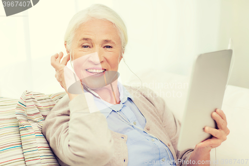 Image of senior woman with tablet pc and earphones at home