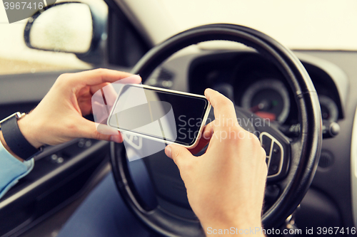 Image of close up of man hand with smartphone driving car