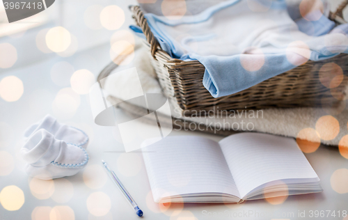 Image of close up of baby clothes for newborn and notebook