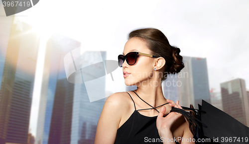 Image of happy woman in black sunglasses with shopping bags