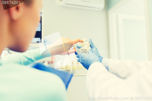 Image of close up of dentist with teeth model and patient