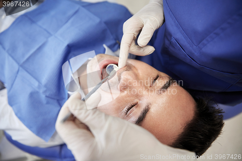 Image of close up of dentist checking male patient teeth