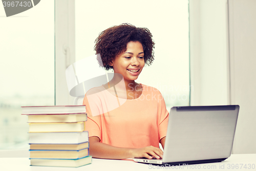 Image of happy african american woman with laptop at home