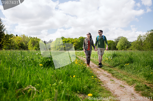 Image of happy couple with backpacks hiking outdoors