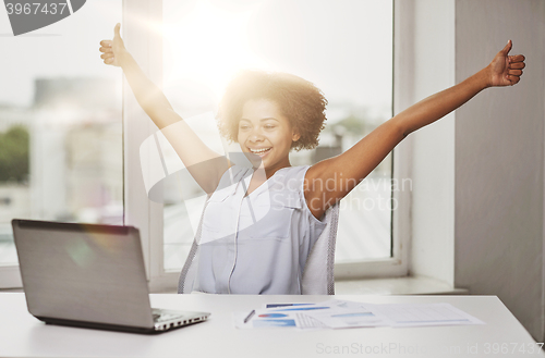 Image of happy african woman with laptop at office