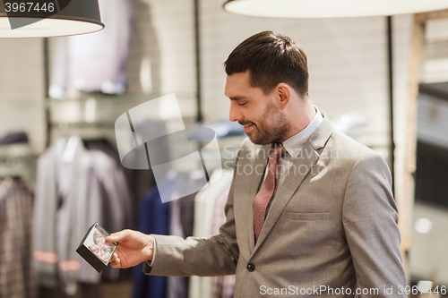 Image of happy young man choosing bow-tie in clothing store