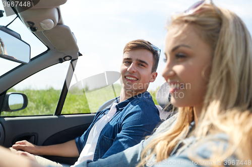 Image of happy couple driving in cabriolet car outdoors