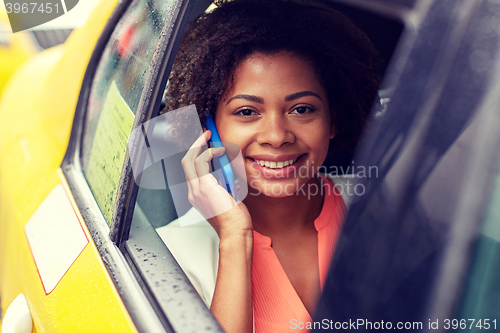 Image of happy african woman calling on smartphone in taxi