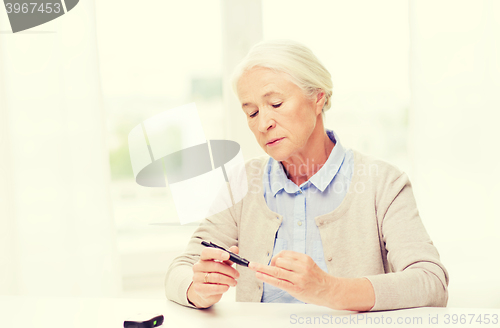 Image of senior woman with glucometer checking blood sugar