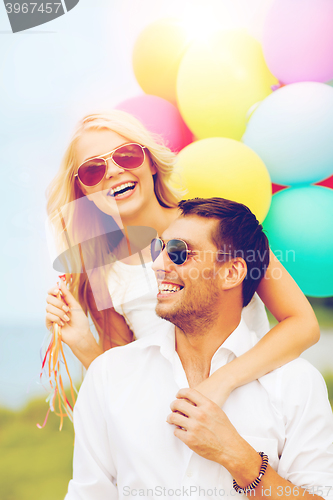 Image of couple with colorful balloons at seaside