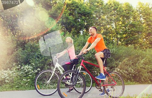 Image of happy couple riding bicycle outdoors