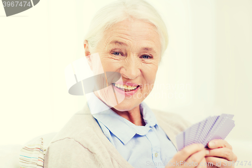 Image of happy senior woman playing cards at home