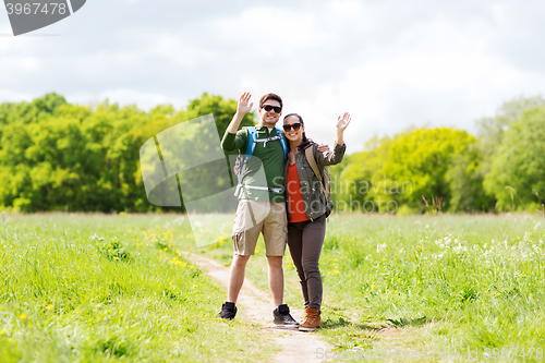 Image of happy couple with backpacks hiking outdoors