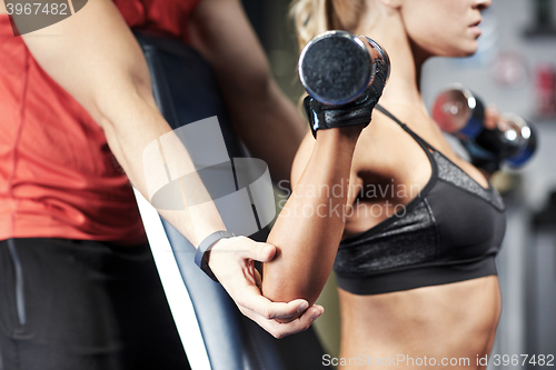 Image of man and woman with dumbbells in gym