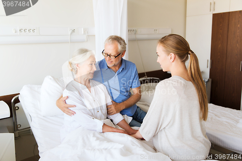 Image of happy family visiting senior woman at hospital