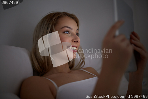 Image of young woman with tablet pc in bed at home bedroom