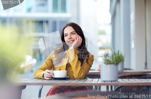 Image of happy woman drinking cocoa at city street cafe