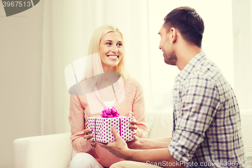 Image of happy man giving woman gift box at home