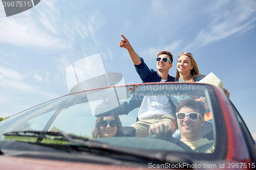 Image of happy friends driving in cabriolet car