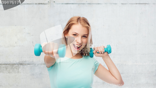 Image of smiling beautiful young sporty woman with dumbbell