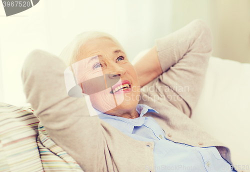 Image of happy senior woman resting on sofa at home