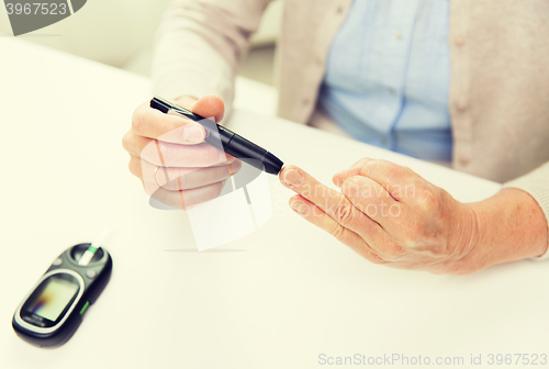 Image of senior woman with glucometer checking blood sugar