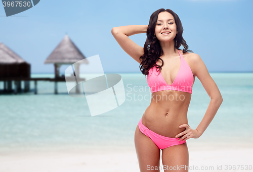 Image of happy young woman in pink bikini swimsuit on beach