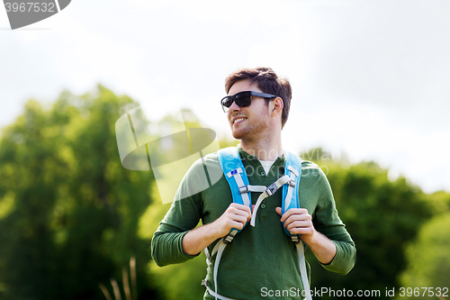 Image of happy young man with backpack hiking outdoors