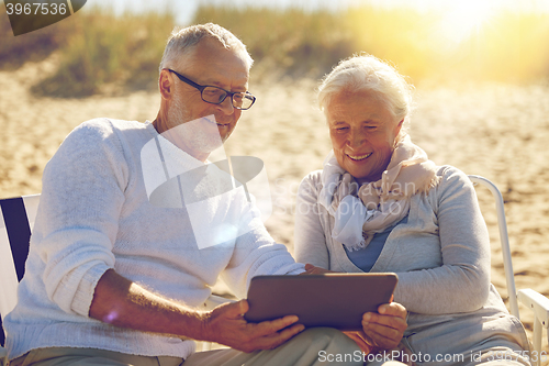 Image of happy senior couple with tablet pc on summer beach