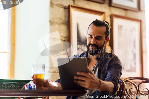 Image of man with tablet pc drinking beer at bar or pub
