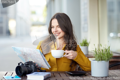 Image of happy woman with map drinking cocoa at city cafe