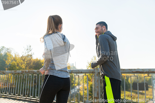 Image of happy couple with earphones running outdoors