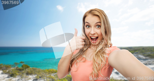 Image of happy woman taking selfie and showing thumbs up