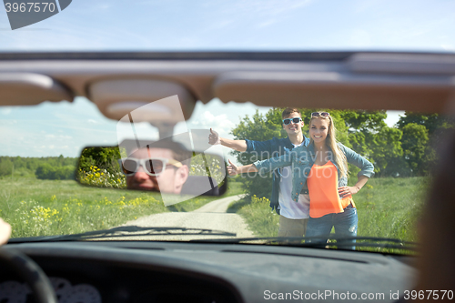 Image of couple hitchhiking and stopping car on countryside