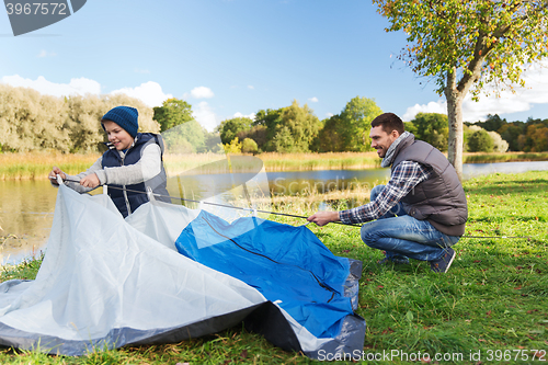 Image of happy father and son setting up tent outdoors