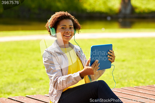 Image of happy african woman with tablet pc and headphones