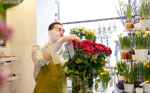 Image of smiling florist man with roses at flower shop