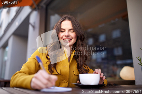 Image of happy woman with notebook drinking cocoa at cafe