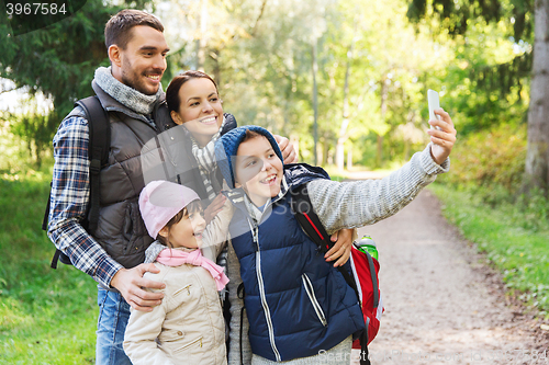 Image of family with backpacks taking selfie by smartphone