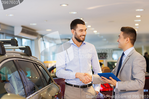 Image of happy man shaking hands in auto show or salon