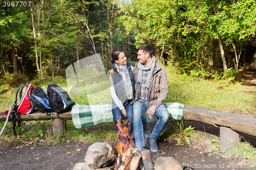 Image of happy couple sitting on bench near camp fire