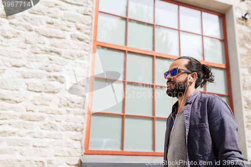 Image of man with earphones listening to music in city