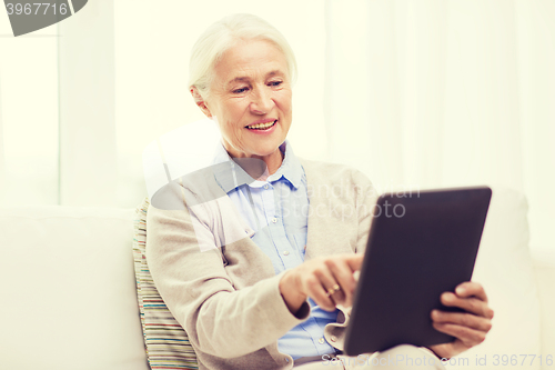 Image of happy senior woman with tablet pc at home