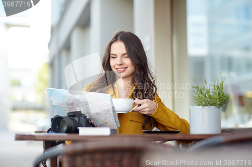 Image of happy woman with map drinking cocoa at city cafe