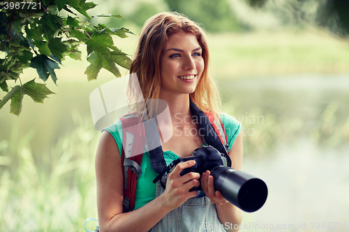 Image of happy woman with backpack and camera outdoors