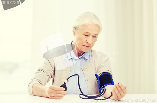 Image of old woman with tonometer checking blood pressure