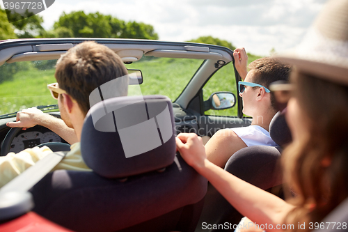 Image of happy friends driving in cabriolet car