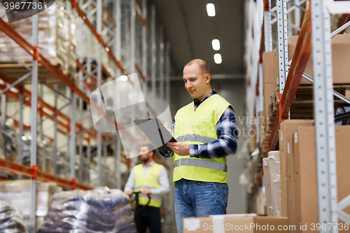 Image of man with clipboard in safety vest at warehouse