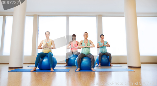 Image of happy pregnant women exercising on fitball in gym