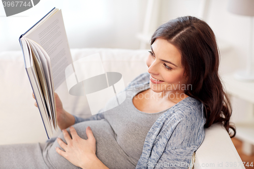 Image of happy pregnant woman reading book at home